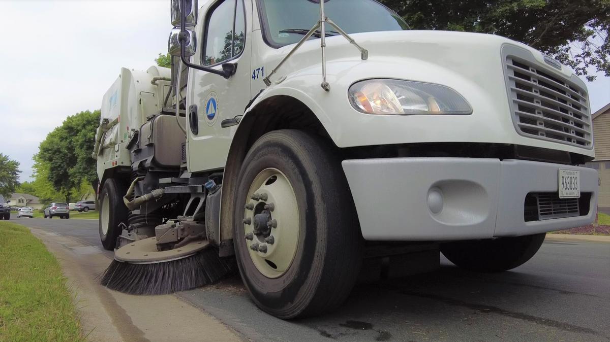 Street sweeping truck showing brush