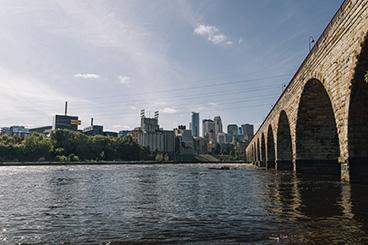 The Stone Arch Bridge crossing the Mississippi River with the Minneapolis skyline in the background.