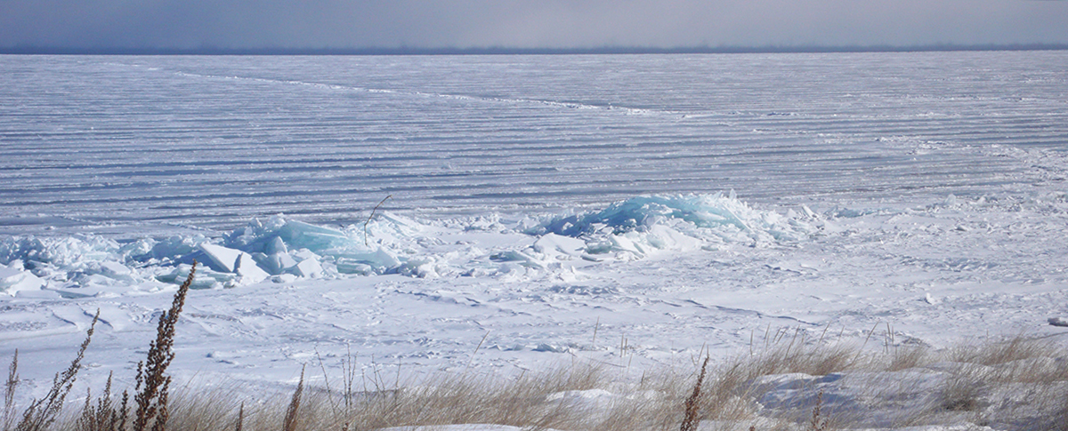 Lake Superior covered with fast ice and a single crack in the ice that extends from shore outward.