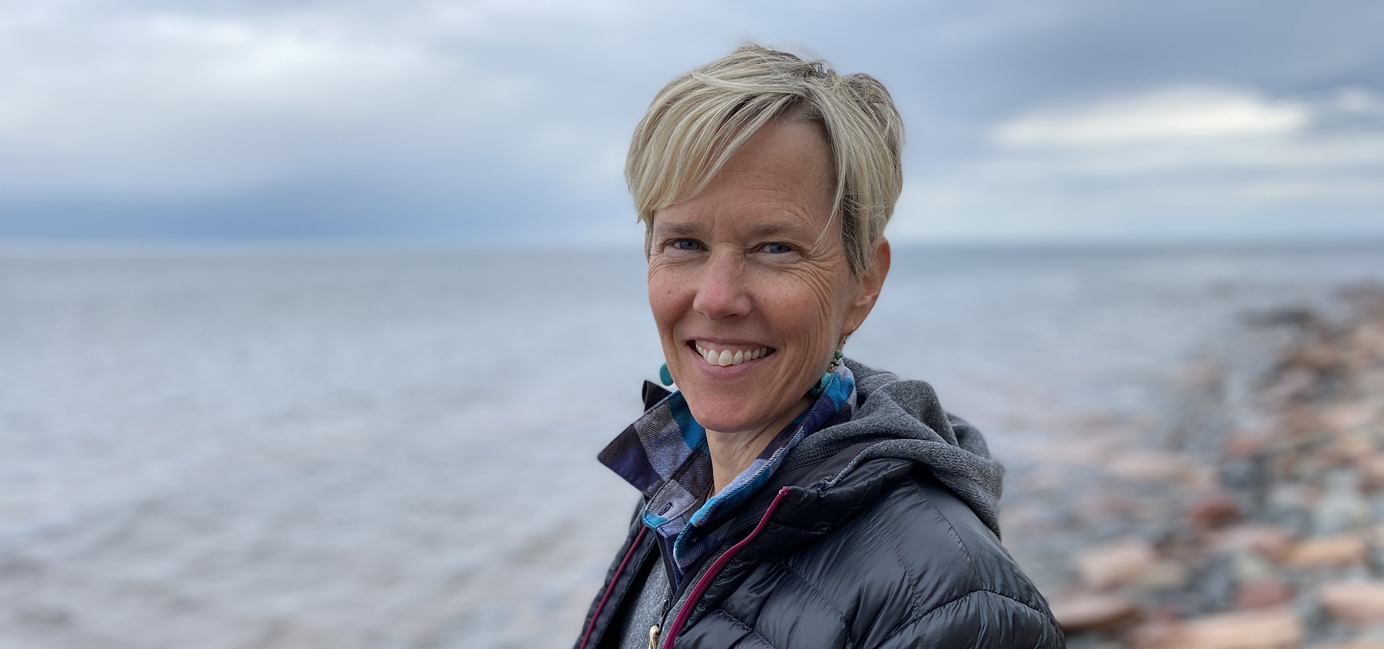 Amy Schrank standing on rocky shoreline of Lake Superior