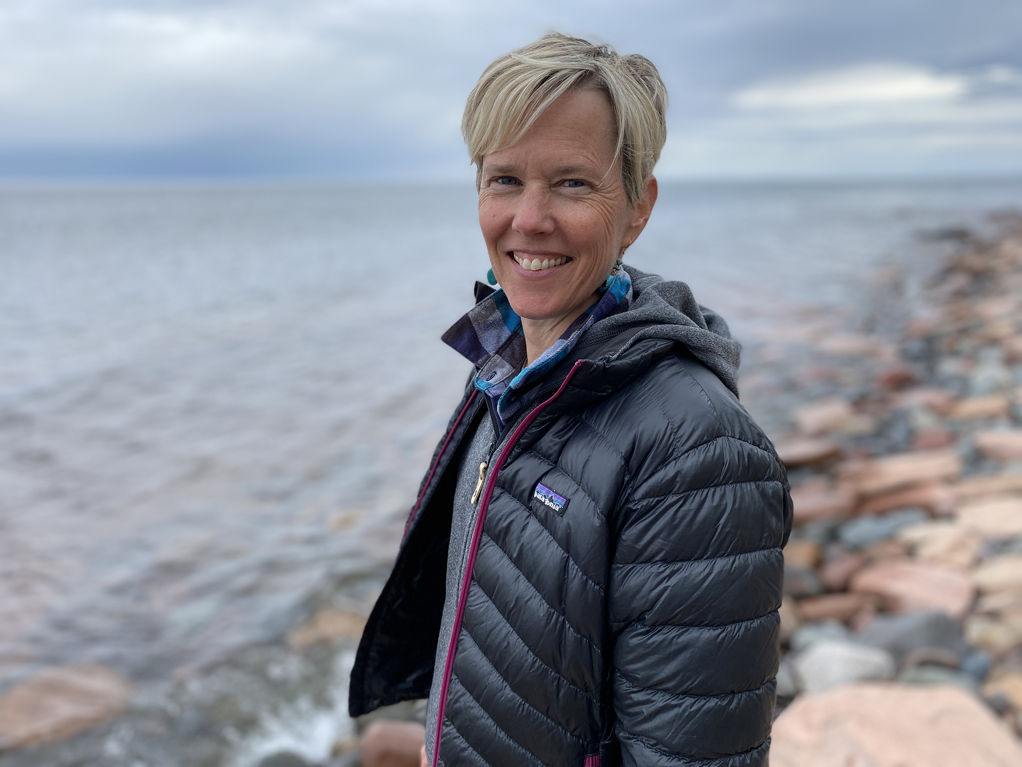 Amy Schrank standing on rocky shoreline of Lake Superior