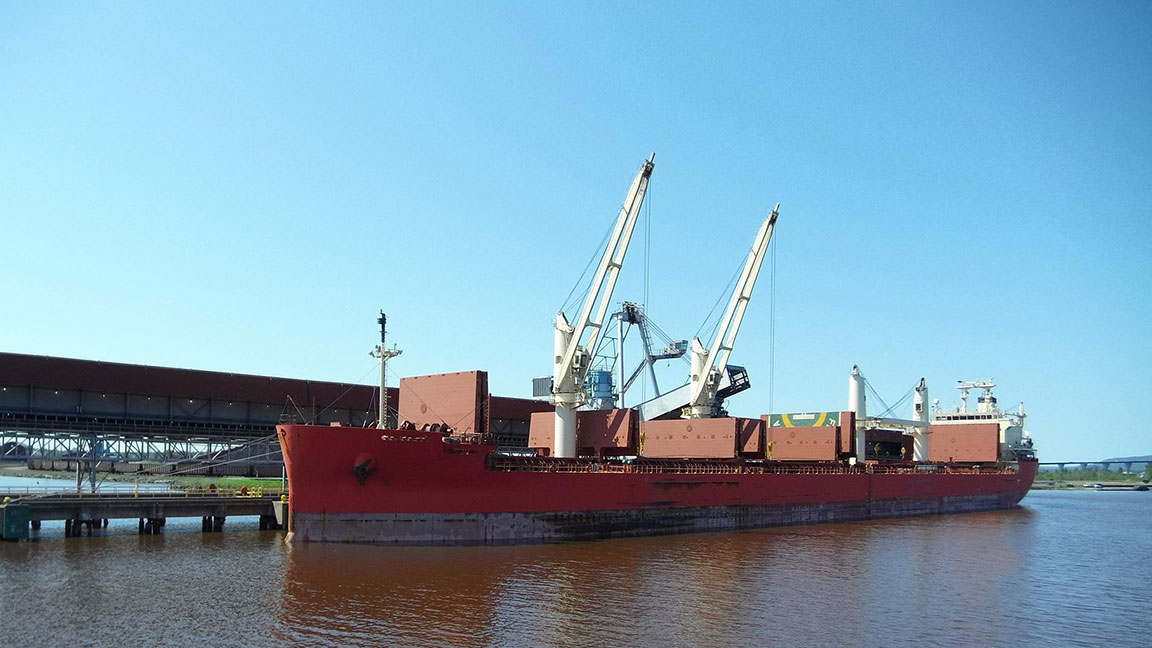 A ship docked in the Duluth-Superior Harbor is being loaded or off-loaded by two cranes.