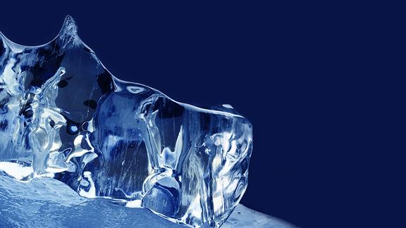 Clear, jagged chunk of ice against a dark blue background.