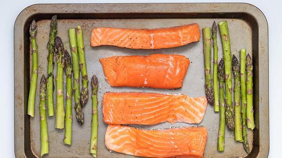 Salmon filets and spears of asparagus on a baking sheet.