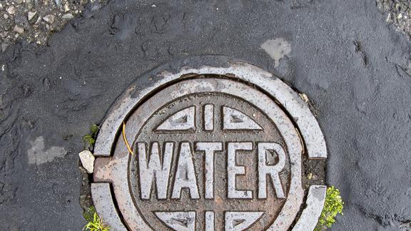 Round, metal, street-level utility cover embossed with the word water 