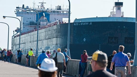 The vessel Walter J. McCarthy Jr passes through the Duluth entry from Lake Superior into the Port of Duluth-Superior. The entry is lined by people watching the vessel.