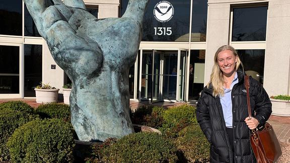2023 Sea Grant Knauss Fellow Mary Collins stands in front of NOAA hand sculpture.