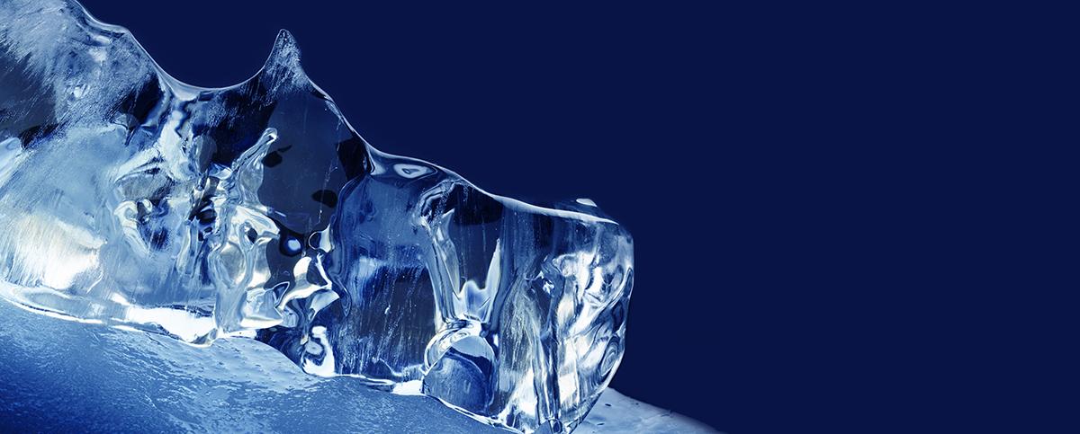 Clear, jagged chunk of ice against a dark blue background.