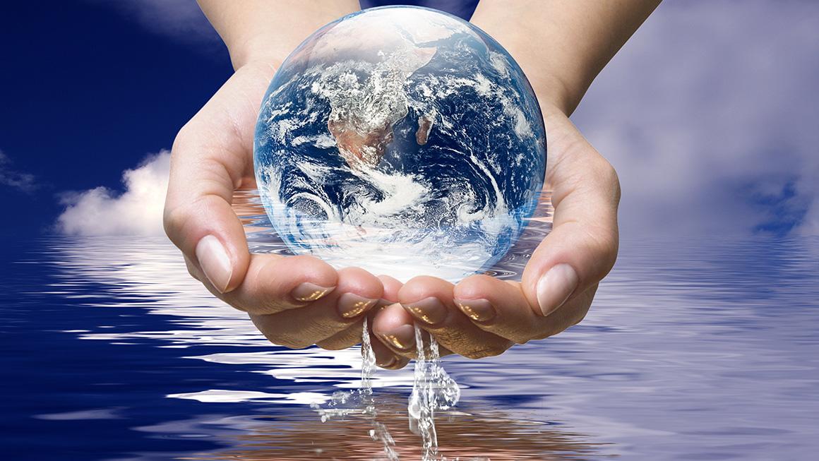 Two hands holding Earth-like ball dripping water over the surface of water