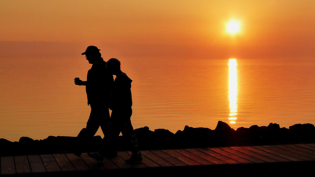 Two people walking the Lakewalk in Duluth, Minnesota during sunset.