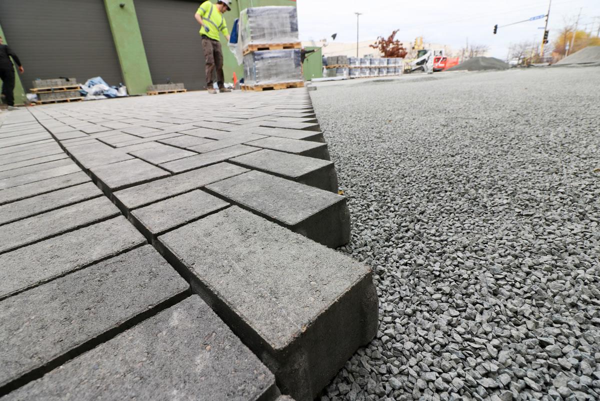 Permeable paving blocks on gravel bed, person in safety vest