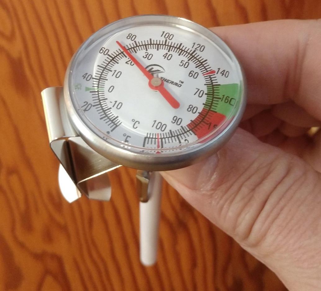 Person's hand holding a hot-drink thermometer. 