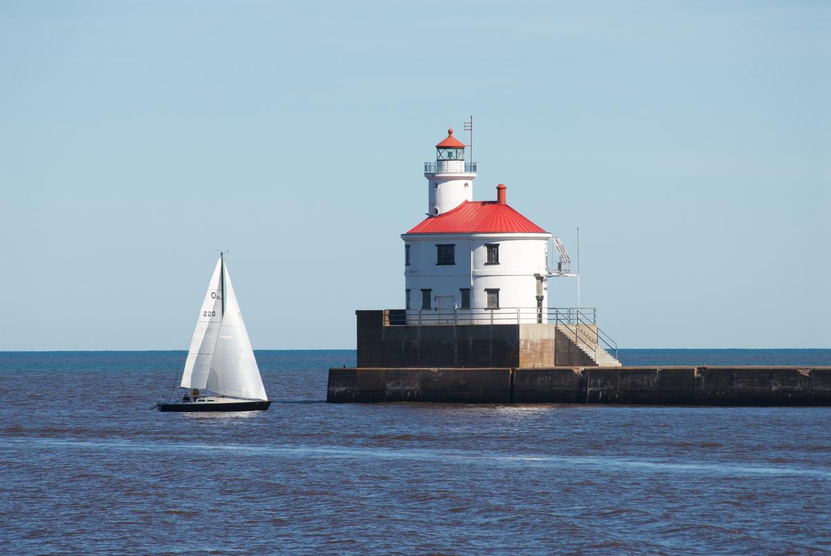 A sailboat passing by a lighthouse on Lake Superior.