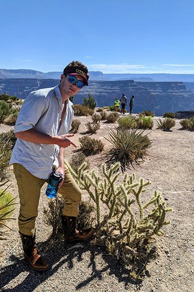Minnesota Sea Grant Student Worker John Emmer posing next to a cactus in the Grand Canyon National Park in Arizona.